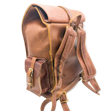 A brown leather backpack with a crocodile-embossed texture, featuring a front pocket with a buckle strap, dual shoulder straps, and gold-tone hardware, photographed on a white background.