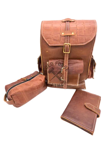 A brown crocodile-embossed leather backpack set with a matching zippered pouch and wallet, displayed on a white background.