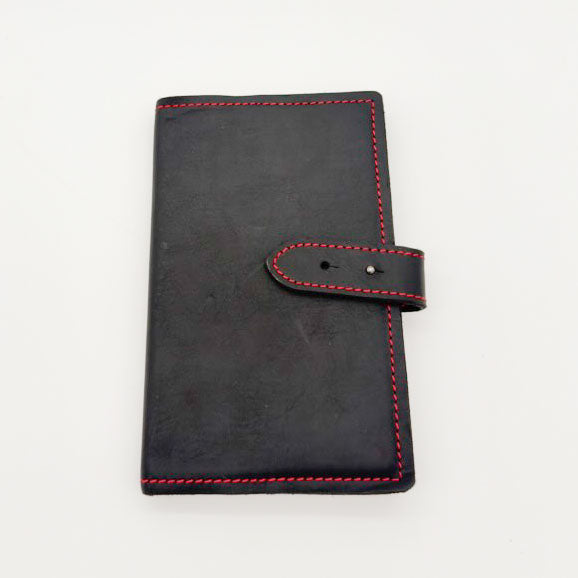 A black leather notebook cover with red contrast stitching and a matching strap closure, shown on a plain white background.