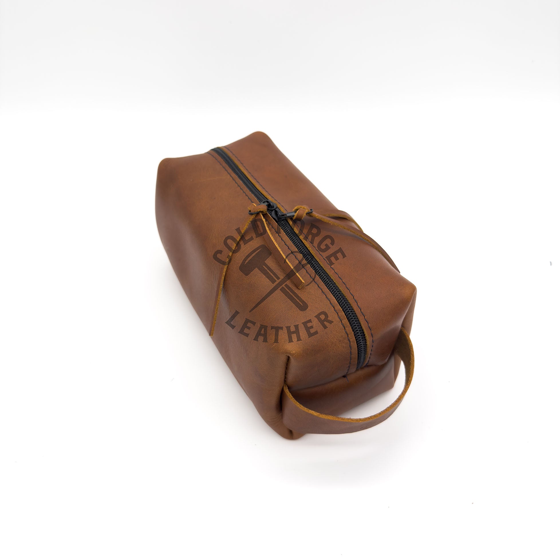 A brown leather toiletry bag with a black zipper and a drawstring closure, fset against a plain white background.