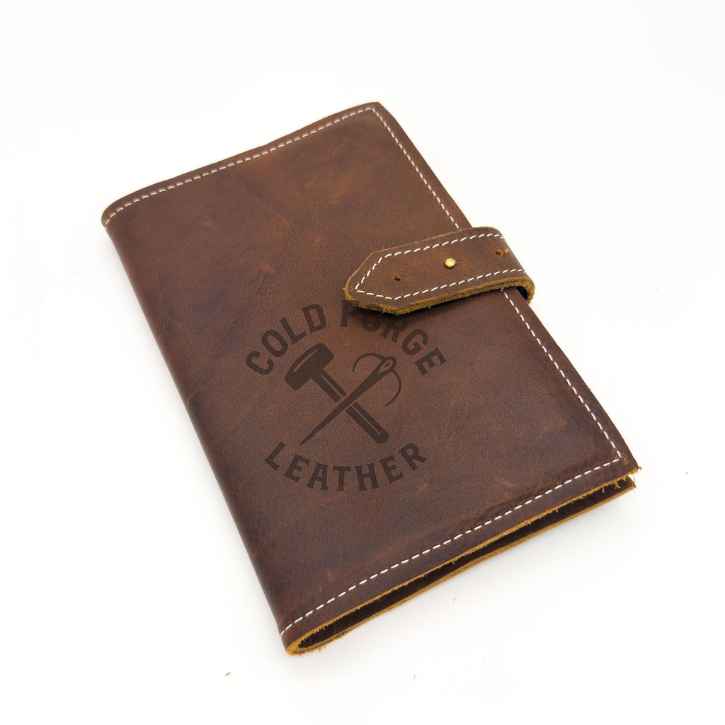 A brown leather wallet or notebook cover with white contrast stitching, a snap tab closure, shown on a white background.